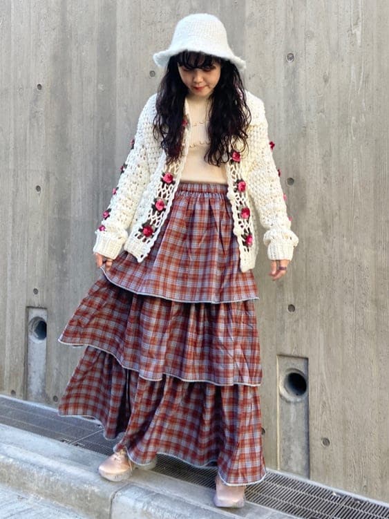 オレンジ系のスカート、オレンジ系のスニーカー、ホワイト系のニット/セーターを着用したレディースの秋コーディネートの2枚目の写真