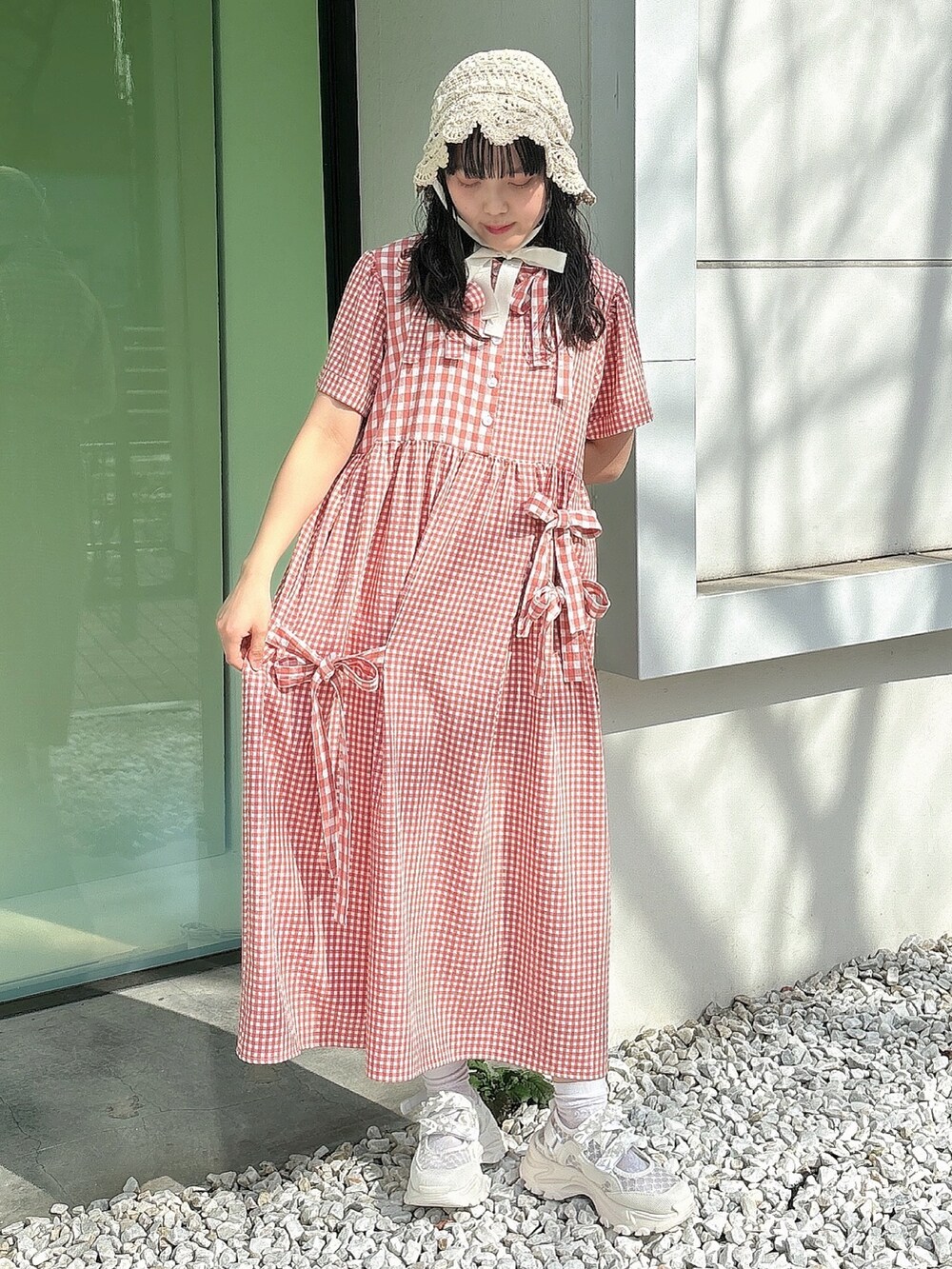 レッド系のワンピース、ホワイト系のスニーカー、ホワイト系のハットを着用したレディースの春コーディネートの2枚目の写真