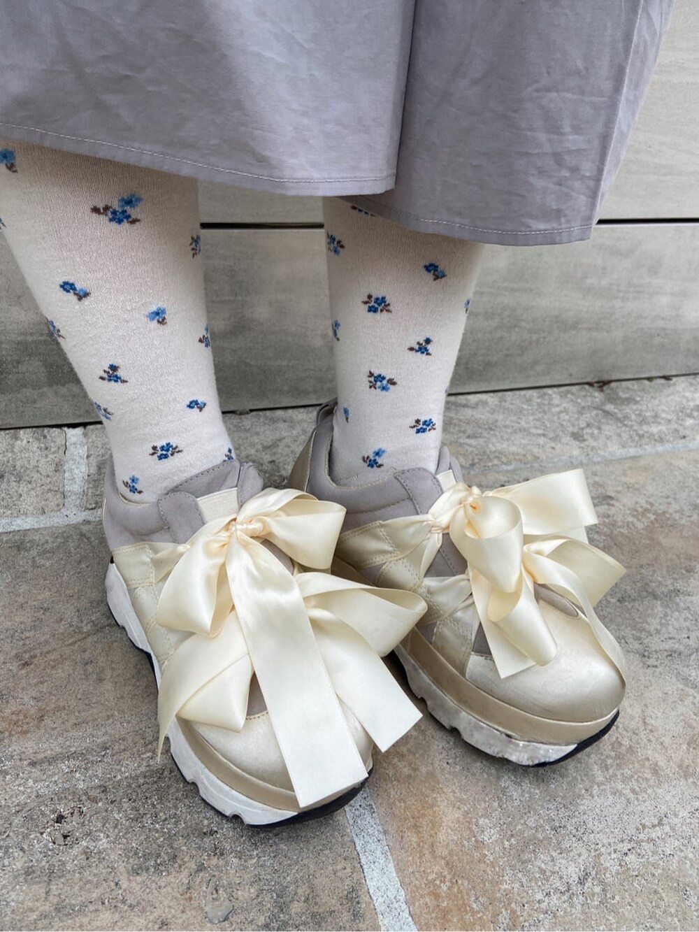 ホワイト系のカーディガン/ボレロ、ホワイト系のスニーカー、グレー系のワンピースを着用したレディースの冬コーディネートの7枚目の写真