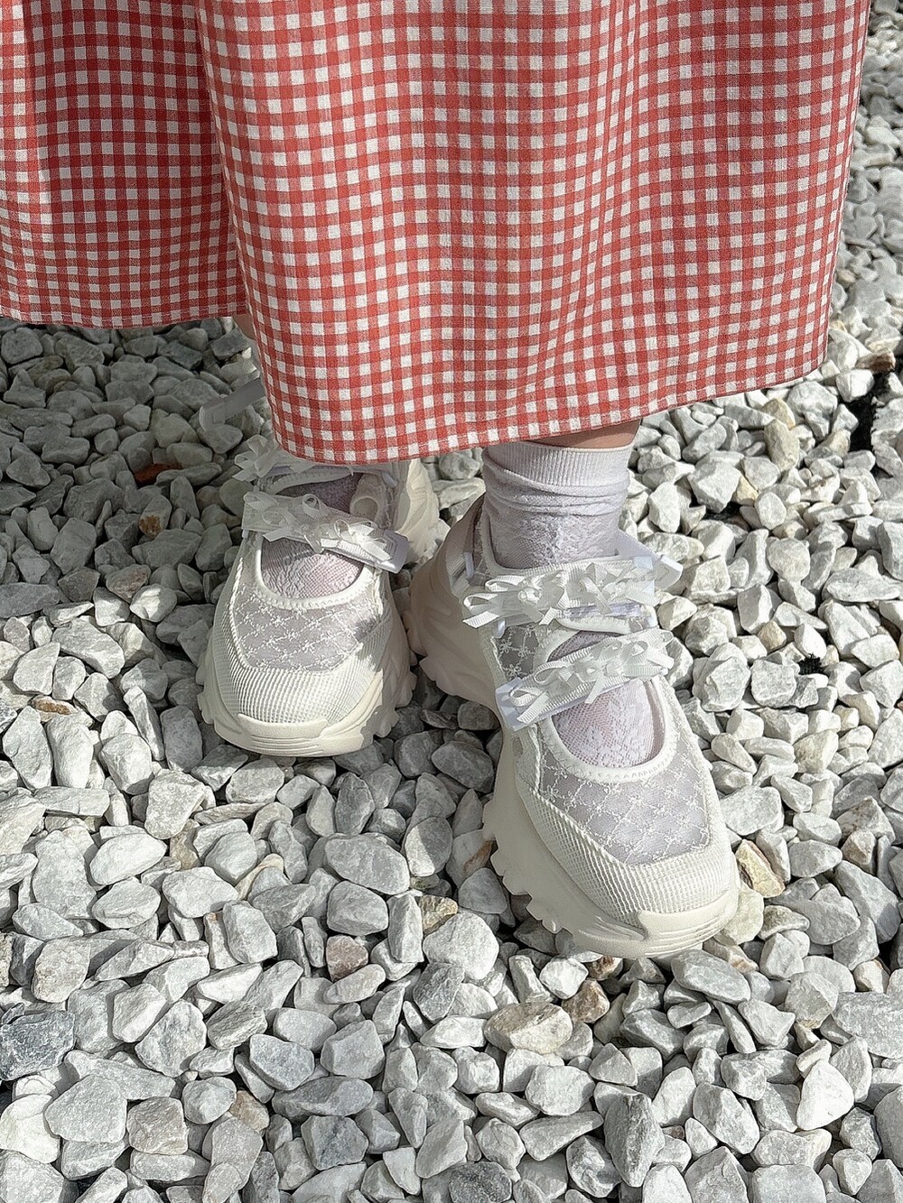 レッド系のワンピース、ホワイト系のスニーカー、ホワイト系のハットを着用したレディースの春コーディネートの8枚目の写真