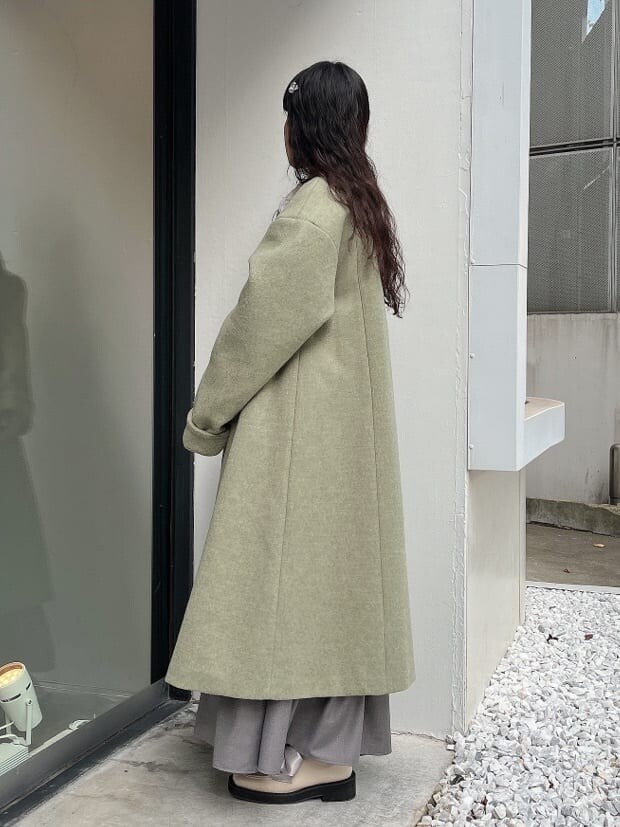 グリーン系のノーカラーコート、ホワイト系のシャツ/ブラウス、ホワイト系のモカシン/デッキシューズを着用したレディースの秋コーディネートの2枚目の写真