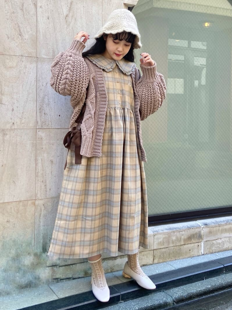 ベージュ系のワンピース、ホワイト系のパンプス、ブラウン系のカーディガン/ボレロを着用したレディースの秋コーディネートの2枚目の写真