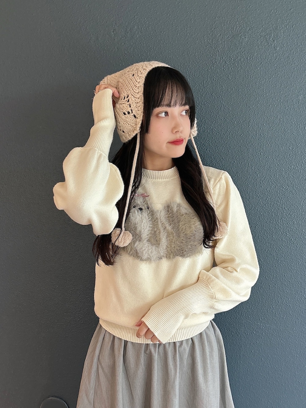 ホワイト系のニット/セーター、グレー系のスカート、ホワイト系のスニーカーを着用したレディースの秋コーディネートの6枚目の写真
