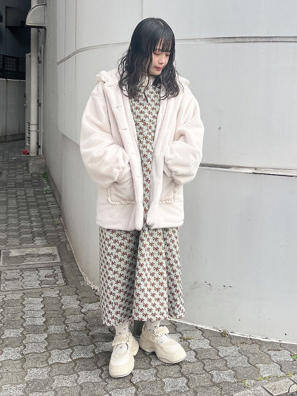 ホワイト系のニット/セーター、ホワイト系のダウンジャケット/コート、グリーン系のジャンパースカートを着用したレディースの冬コーディネートの2枚目の写真