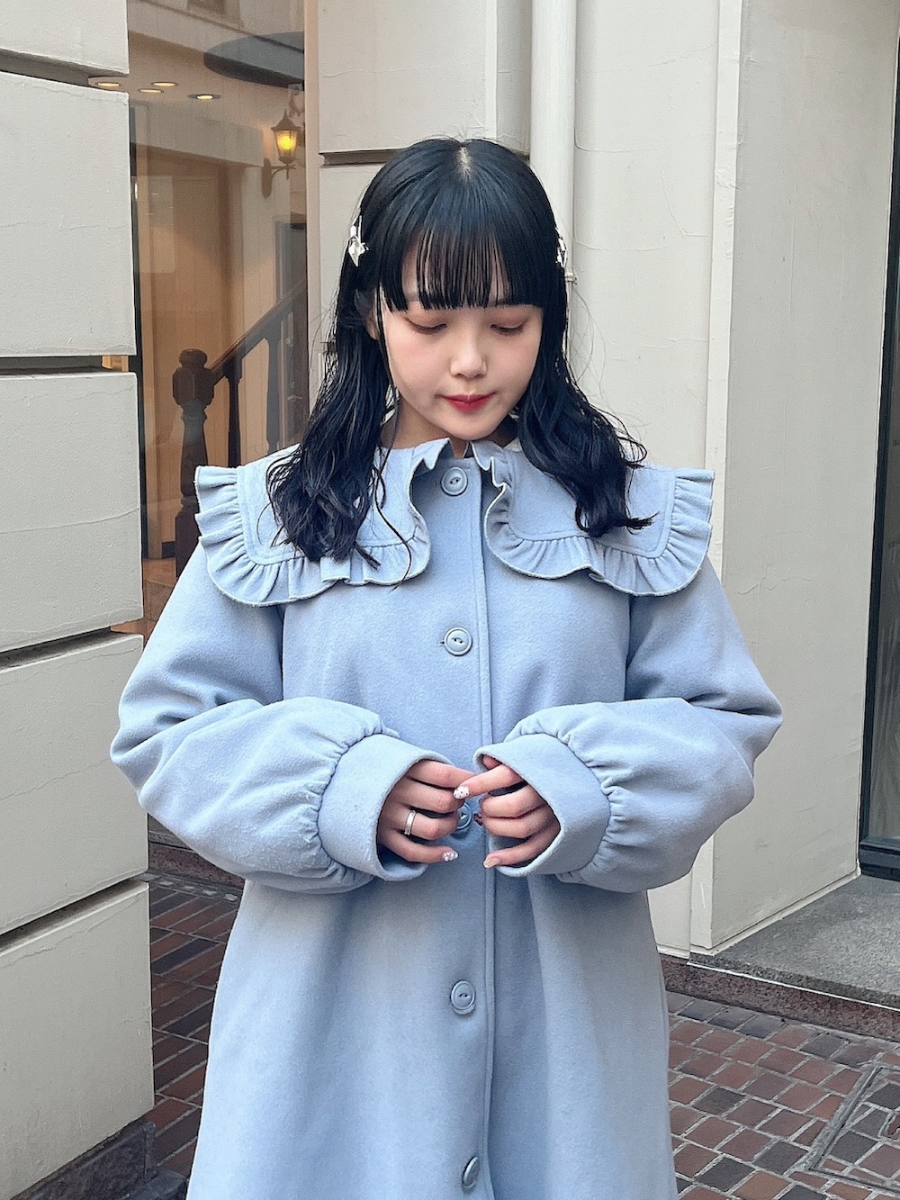 ブルー系のチェスターコート、グリーン系のスカート、ホワイト系のスニーカーを着用したレディースの冬コーディネートの5枚目の写真