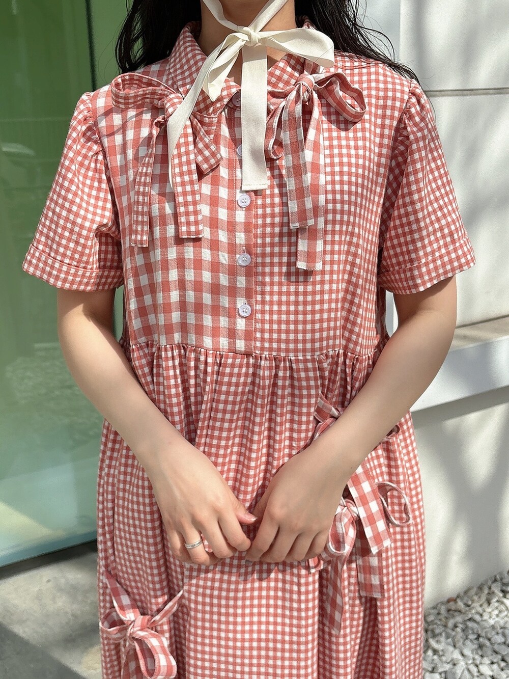 レッド系のワンピース、ホワイト系のスニーカー、ホワイト系のハットを着用したレディースの春コーディネートの7枚目の写真