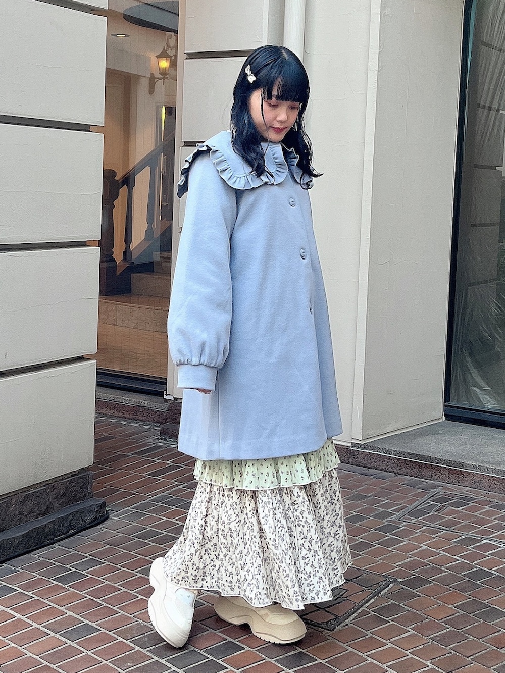ブルー系のチェスターコート、グリーン系のスカート、ホワイト系のスニーカーを着用したレディースの冬コーディネートの2枚目の写真