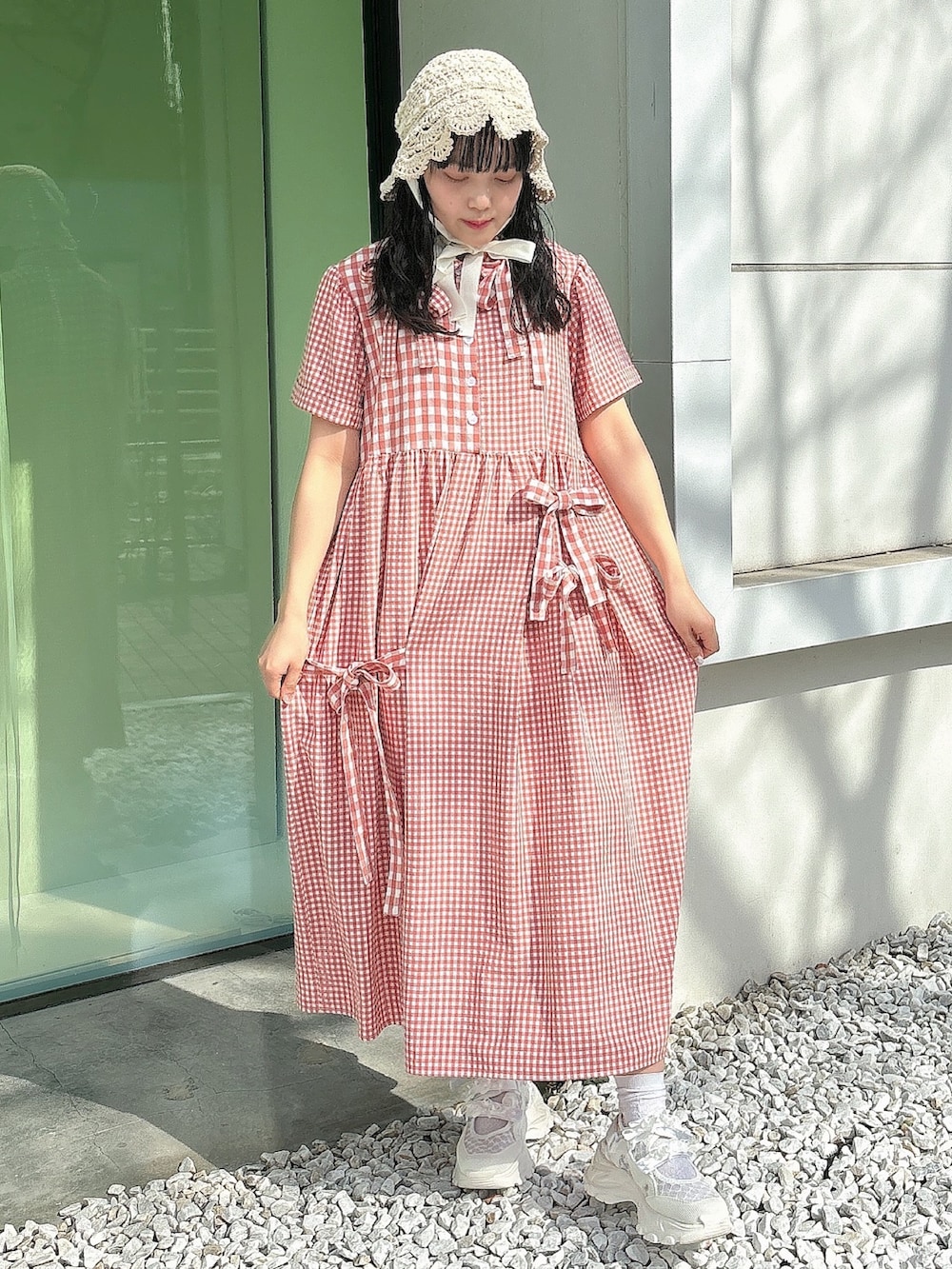 レッド系のワンピース、ホワイト系のスニーカー、ホワイト系のハットを着用したレディースの春コーディネートの3枚目の写真