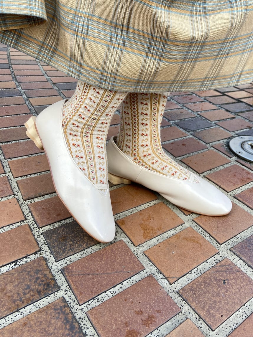 ベージュ系のワンピース、ホワイト系のパンプス、ブラウン系のカーディガン/ボレロを着用したレディースの秋コーディネートの6枚目の写真