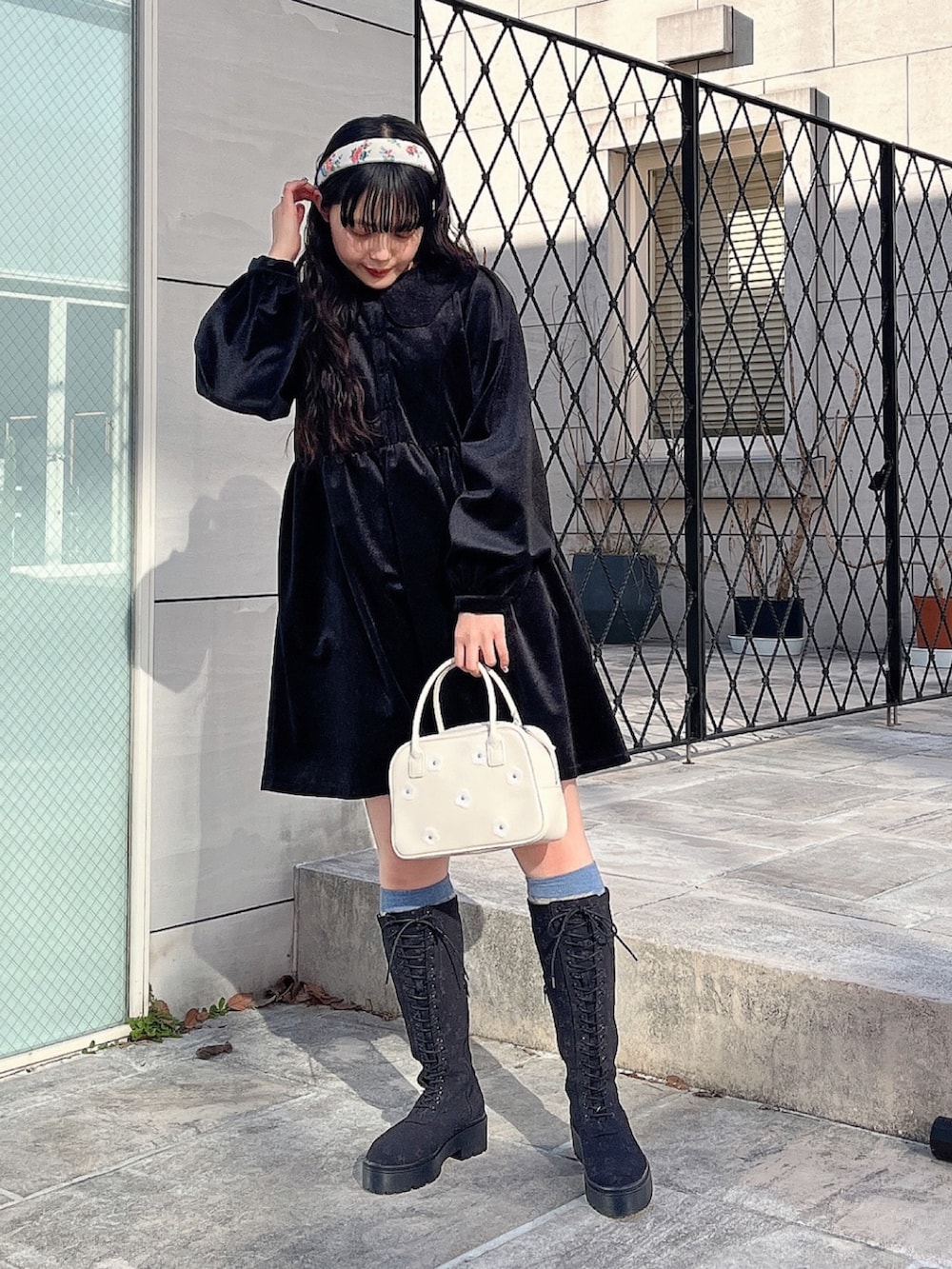 ブラック系のワンピース、ホワイト系のボストンバッグ、ブラック系のブーツを着用したレディースの冬コーディネートの2枚目の写真