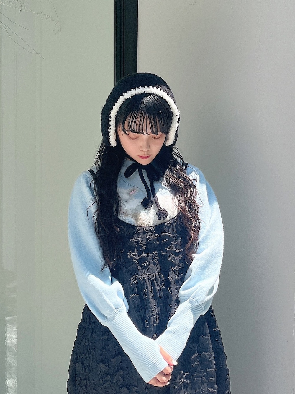 ブルー系のニット/セーター、ブラック系のワンピース、ホワイト系のスリッポンを着用したレディースの夏コーディネートの5枚目の写真