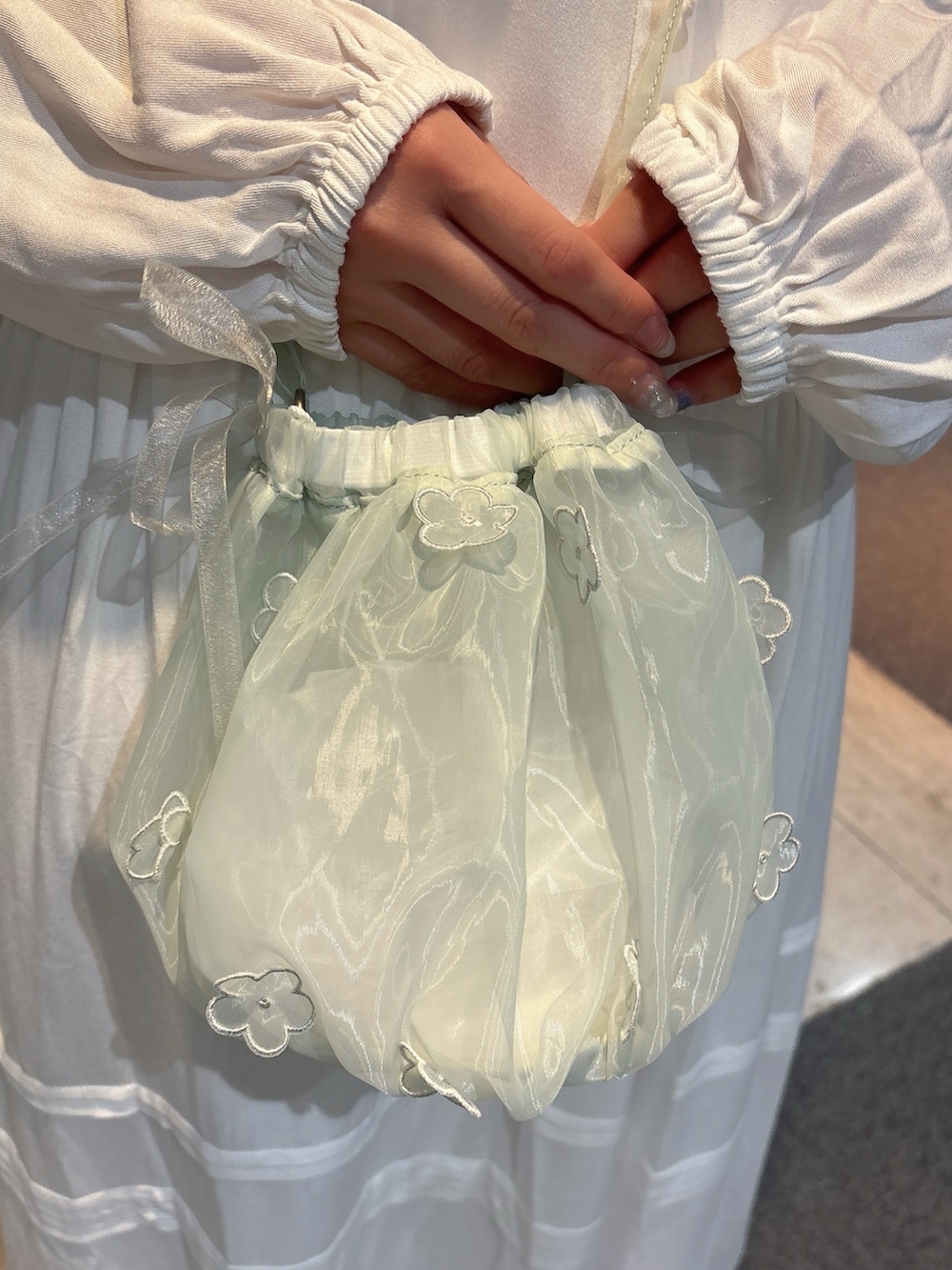 グリーン系のハンドバッグ、ホワイト系のスニーカー、ホワイト系のワンピースを着用したレディースの冬コーディネートの9枚目の写真