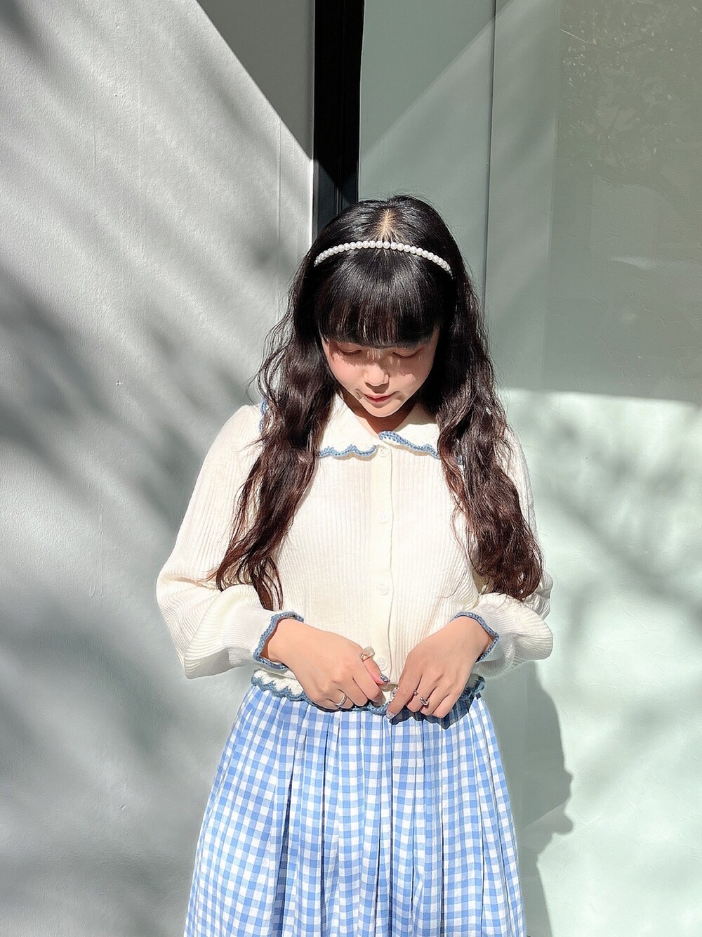 ホワイト系のニット/セーター、ブルー系のスカート、ホワイト系のパンプスを着用したレディースの秋コーディネートの4枚目の写真