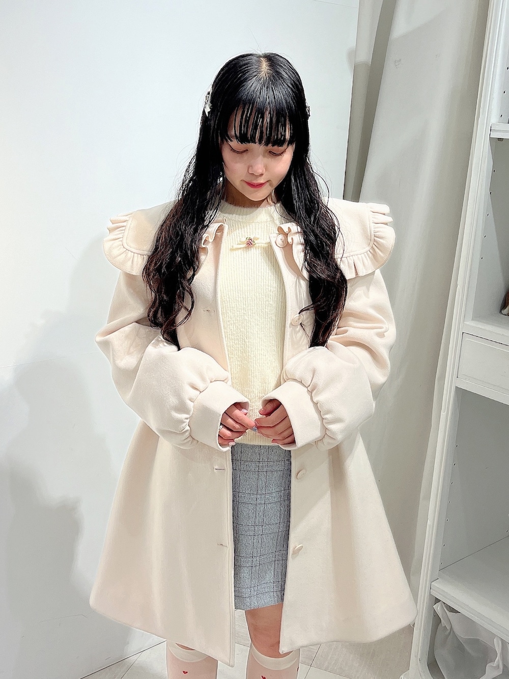 ホワイト系のニット/セーター、ホワイト系のチェスターコート、グレー系のスカートを着用したレディースの冬コーディネートの5枚目の写真