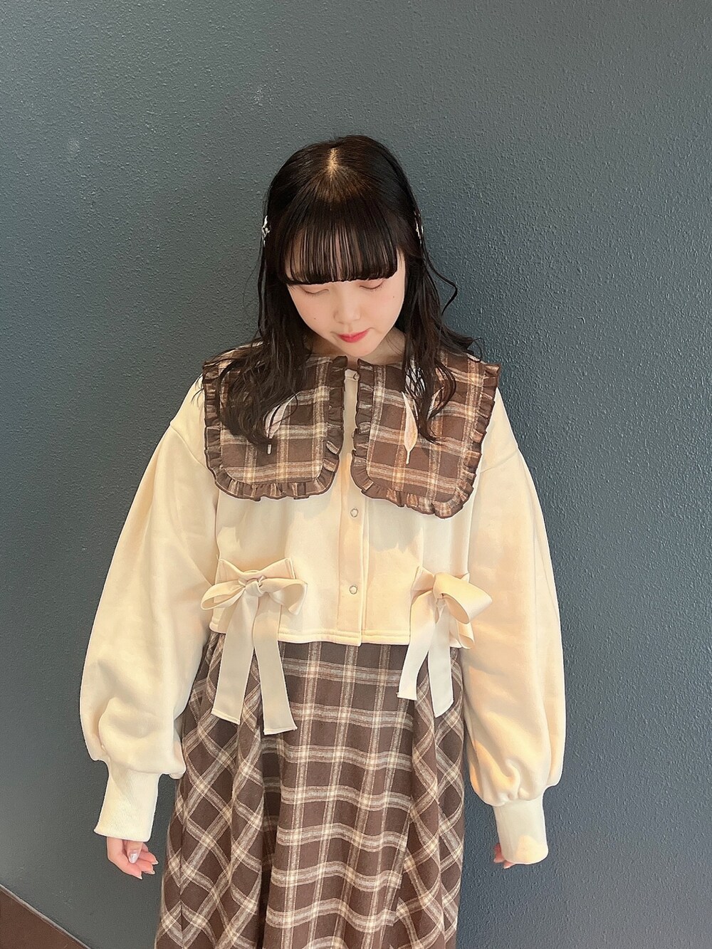 ブラウン系のワンピース、ホワイト系のカーディガン/ボレロ、ホワイト系のスニーカーを着用したレディースの冬コーディネートの4枚目の写真