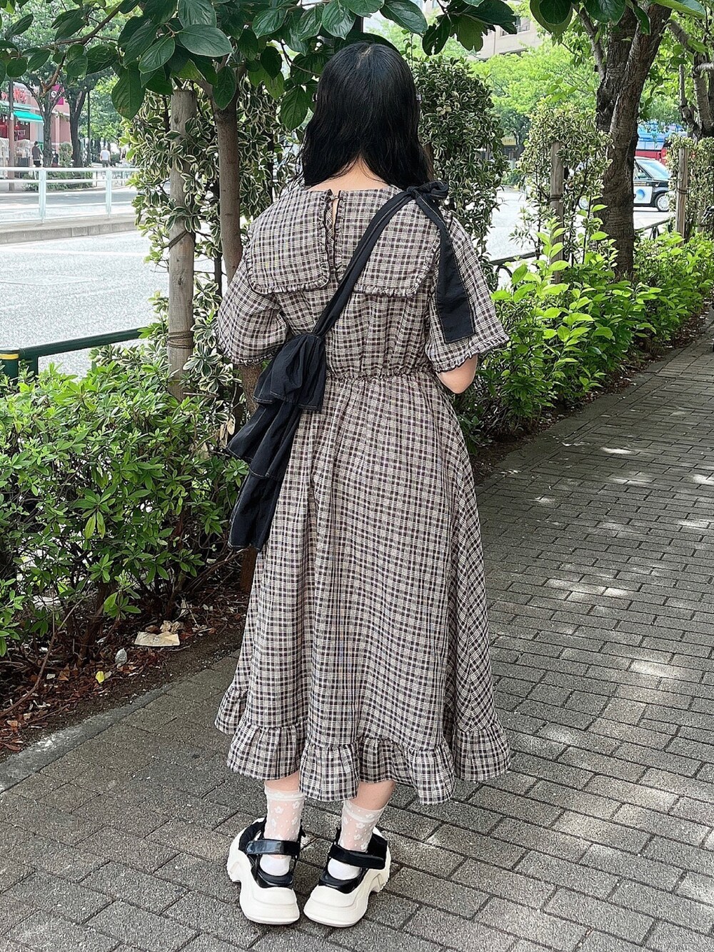 ブラウン系のワンピース、ブラック系のショルダーバッグ、ブラック系のサンダルを着用したレディースの夏コーディネートの3枚目の写真