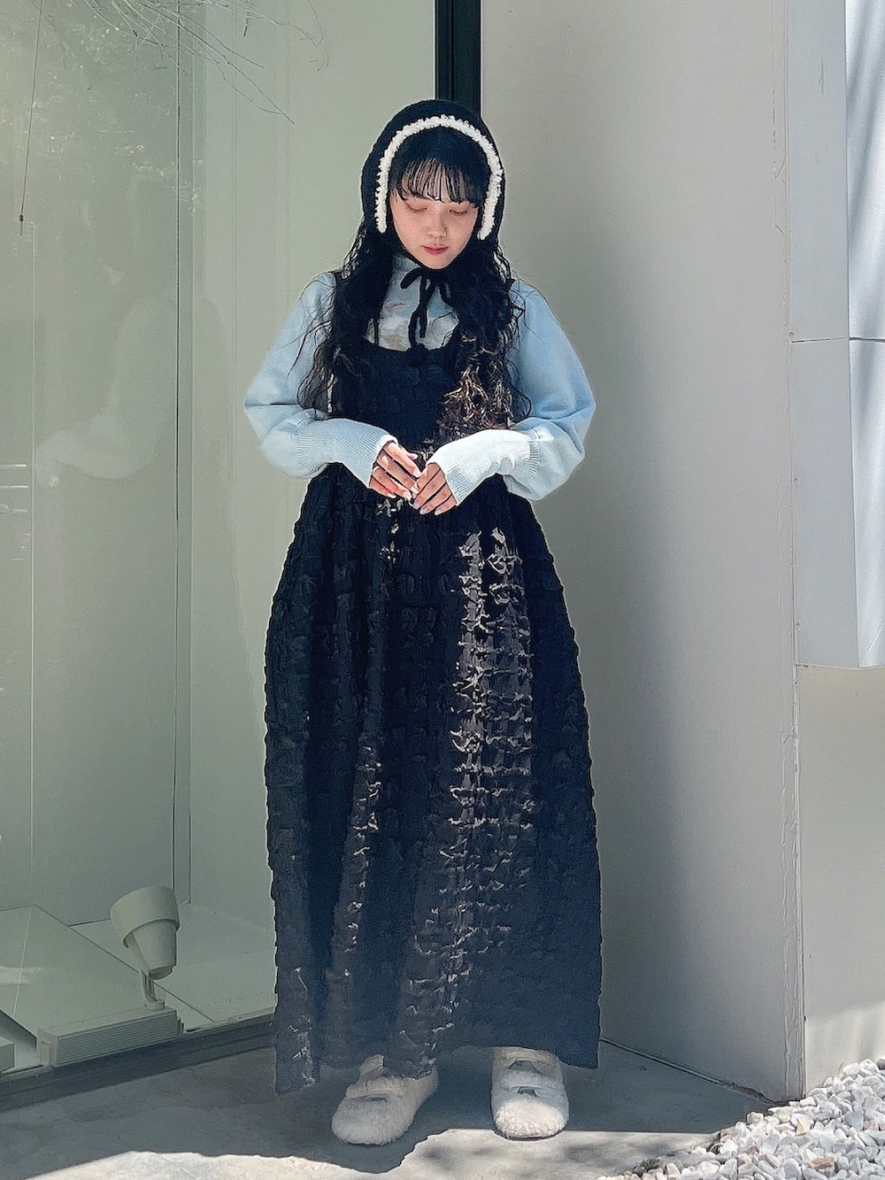 ブルー系のニット/セーター、ブラック系のワンピース、ホワイト系のスリッポンを着用したレディースの夏コーディネートの2枚目の写真