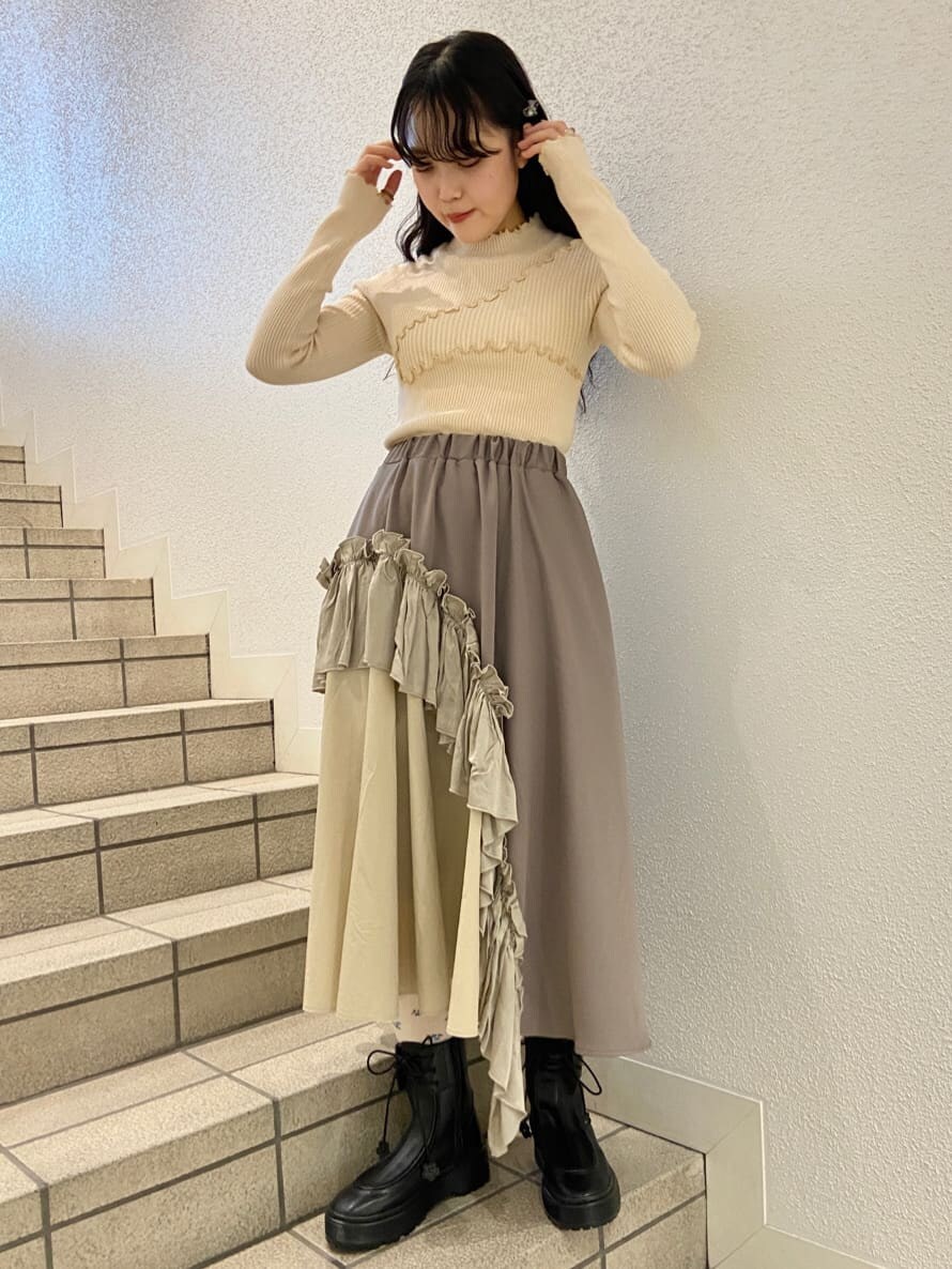 ブラック系のハンドバッグ、ブラック系のブーツ、ベージュ系のスカートを着用したレディースの冬コーディネートの6枚目の写真