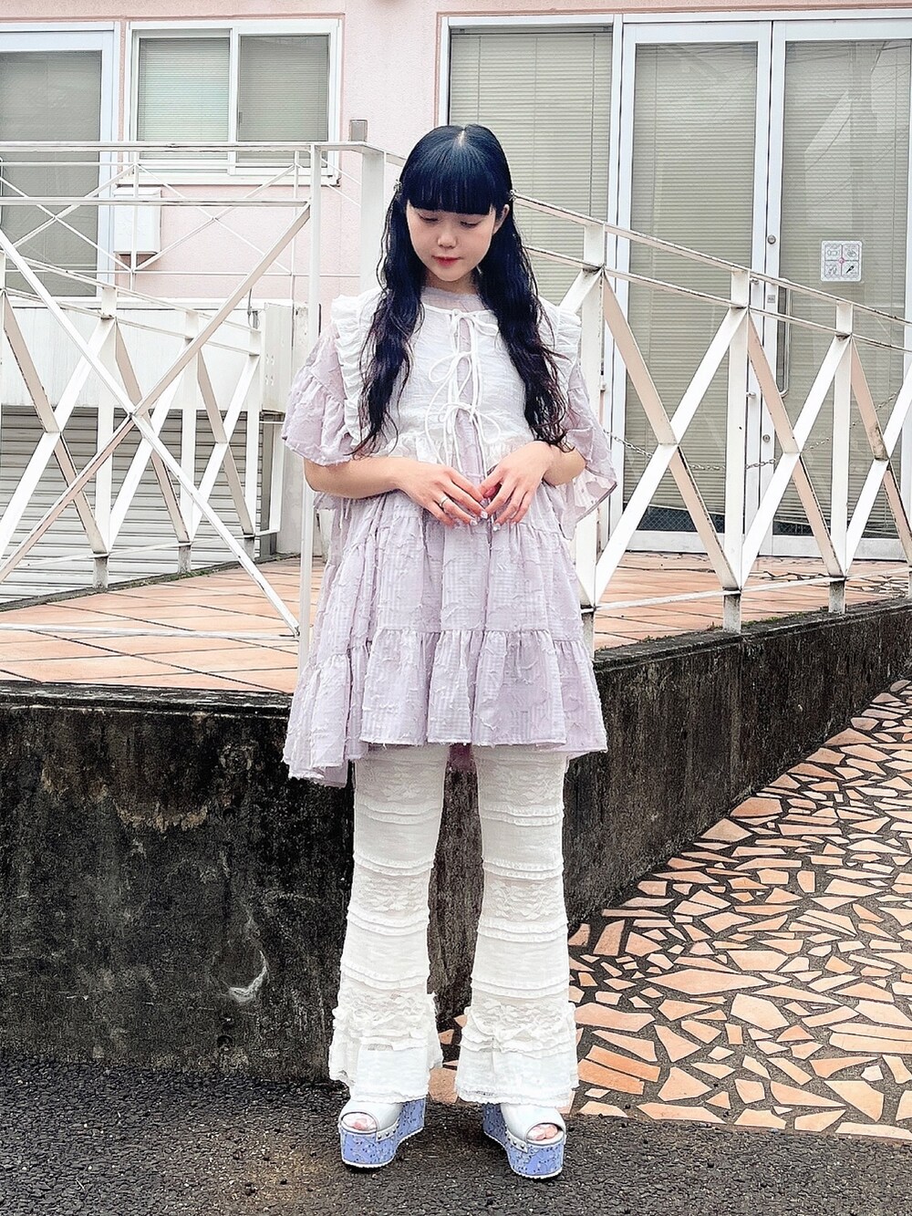 パープル系のワンピース、ホワイト系のスラックス、ブルー系のサンダルを着用したレディースの春コーディネートの2枚目の写真