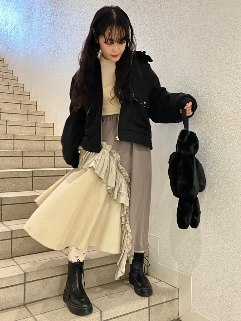 ブラック系のハンドバッグ、ブラック系のブーツ、ベージュ系のスカートを着用したレディースの冬コーディネートの2枚目の写真