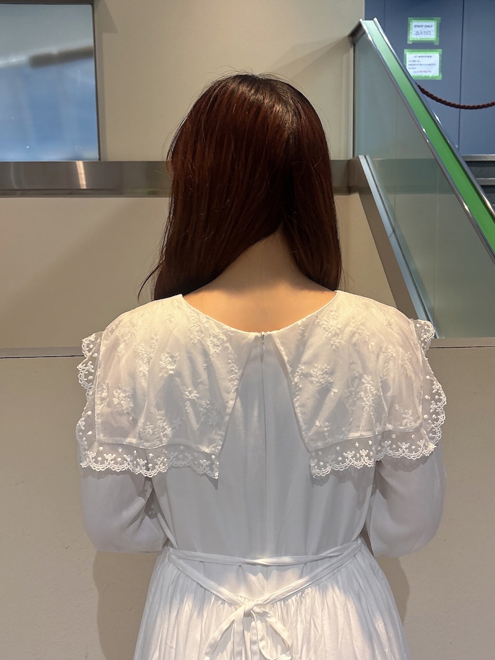 グリーン系のハンドバッグ、ホワイト系のスニーカー、ホワイト系のワンピースを着用したレディースの冬コーディネートの7枚目の写真