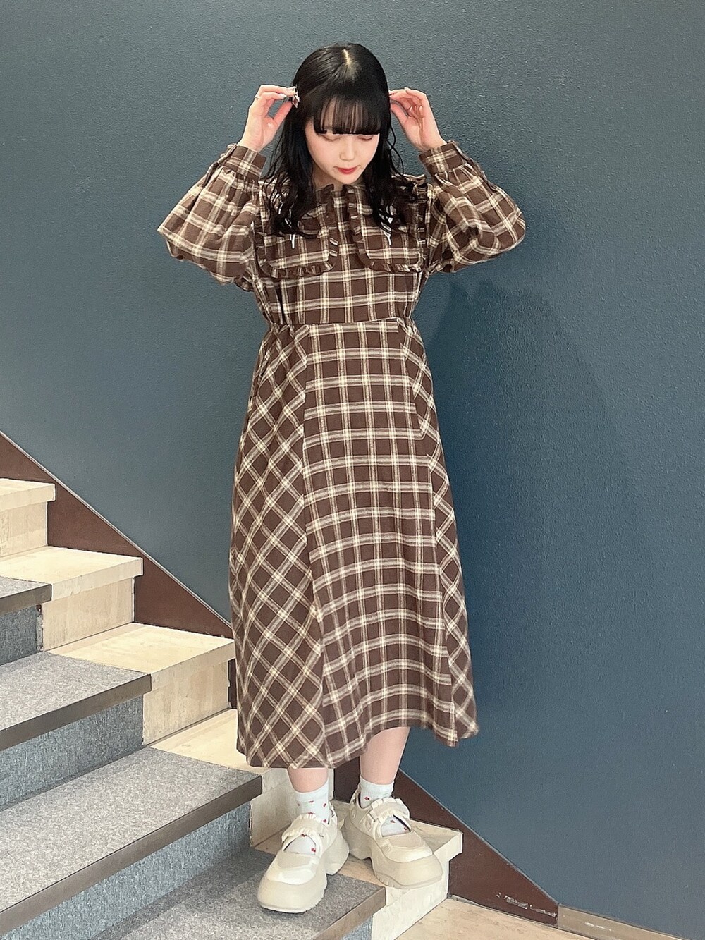 ブラウン系のワンピース、ホワイト系のスニーカーを着用したレディースの冬コーディネートの2枚目の写真