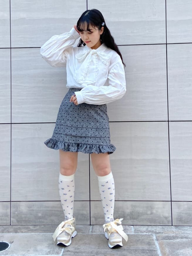 ホワイト系のスニーカー、ホワイト系のカーディガン/ボレロ、グレー系のスカートを着用したレディースの冬コーディネートの3枚目の写真