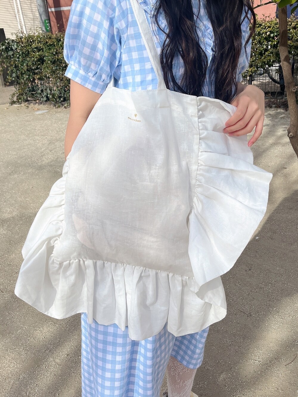 ホワイト系のトートバッグ、ブルー系のワンピース、ホワイト系のスニーカーを着用したレディースの冬コーディネートの6枚目の写真