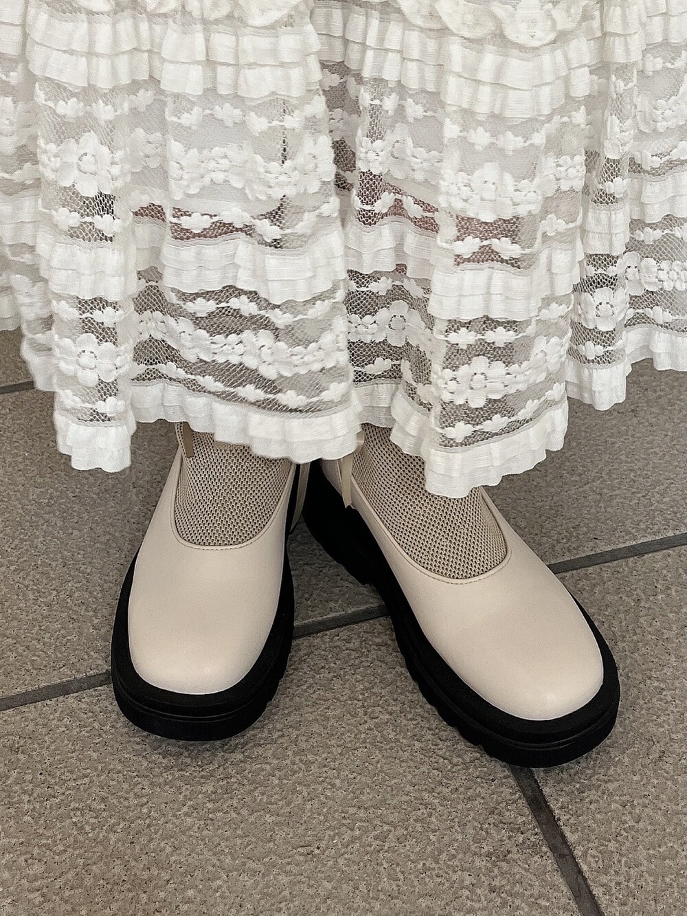 ホワイト系のニット/セーター、ホワイト系のスカート、ホワイト系のブーツを着用したレディースの秋コーディネートの6枚目の写真