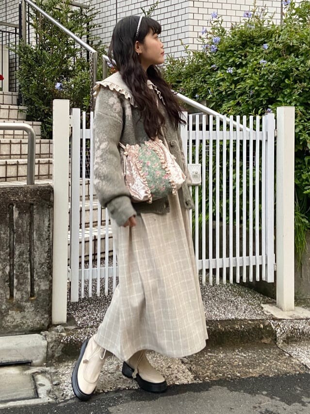 ホワイト系のブーツ、ホワイト系のハンドバッグ、ベージュ系のワンピースを着用したレディースの冬コーディネートの2枚目の写真