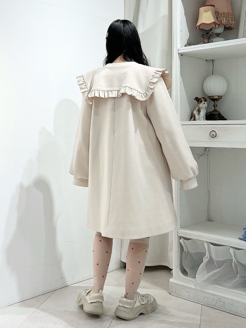 ホワイト系のニット/セーター、ホワイト系のチェスターコート、グレー系のスカートを着用したレディースの冬コーディネートの4枚目の写真