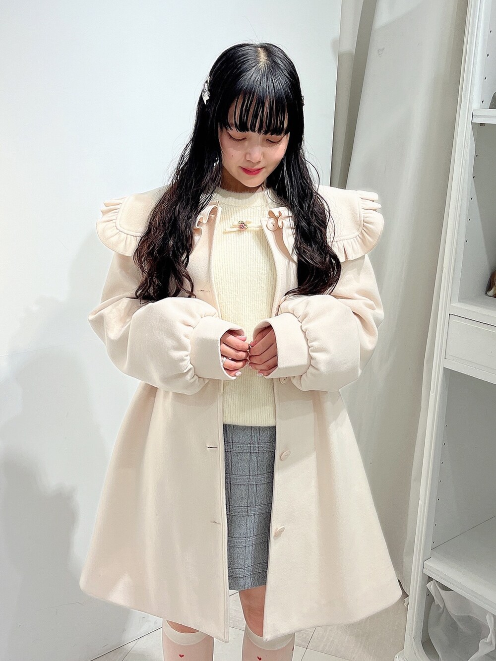 ホワイト系のニット/セーター、ホワイト系のチェスターコート、グレー系のスカートを着用したレディースの冬コーディネートの6枚目の写真