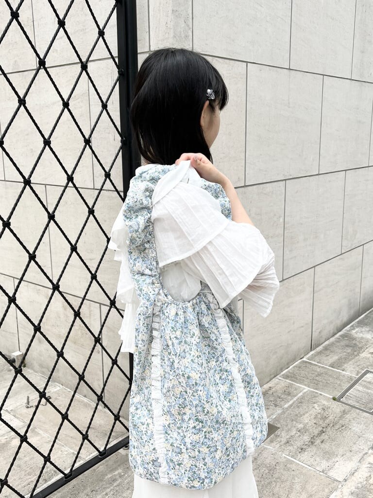 ホワイト系のワンピース、ホワイト系のサンダル、ブルー系のトートバッグを着用したレディースの春コーディネートの3枚目の写真