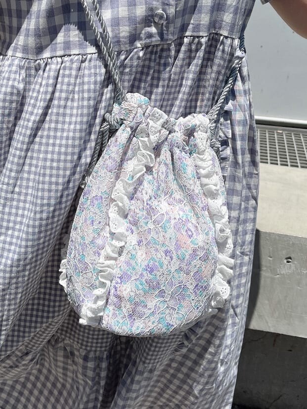 ホワイト系のサンダル、パープル系のハンドバッグ、パープル系のワンピースを着用したレディースの夏コーディネートの4枚目の写真