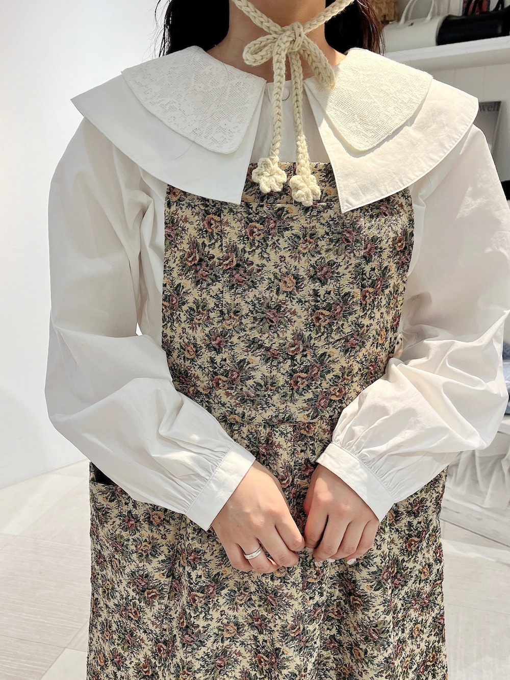 ホワイト系のシャツ/ブラウス、ベージュ系のジャンパースカート、ホワイト系のスニーカーを着用したレディースの秋コーディネートの7枚目の写真