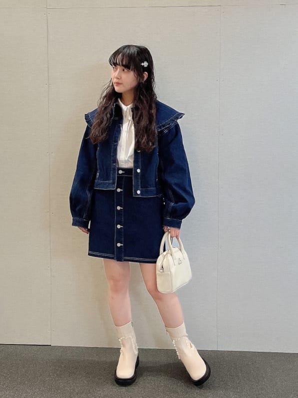 ブルー系のデニムジャケット、ホワイト系のブーツ、ホワイト系のボストンバッグを着用したレディースの夏コーディネートの2枚目の写真