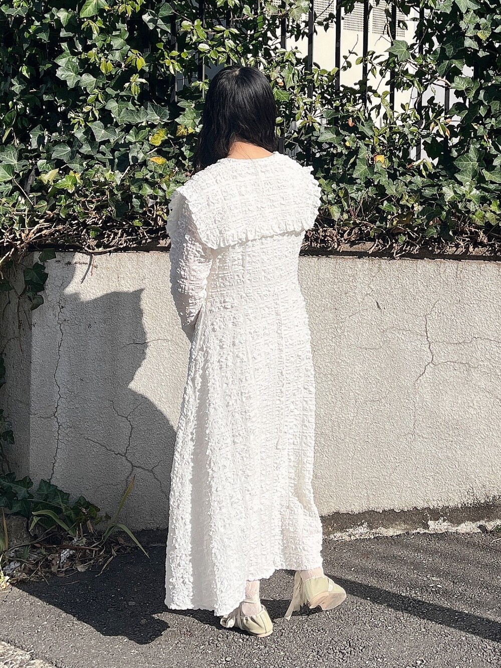 ホワイト系のワンピース、グリーン系のパンプス、シルバー系のイヤリングを着用したレディースの冬コーディネートの4枚目の写真