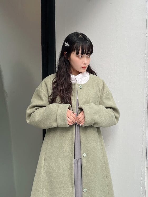 グリーン系のノーカラーコート、ホワイト系のシャツ/ブラウス、ホワイト系のモカシン/デッキシューズを着用したレディースの秋コーディネートの3枚目の写真