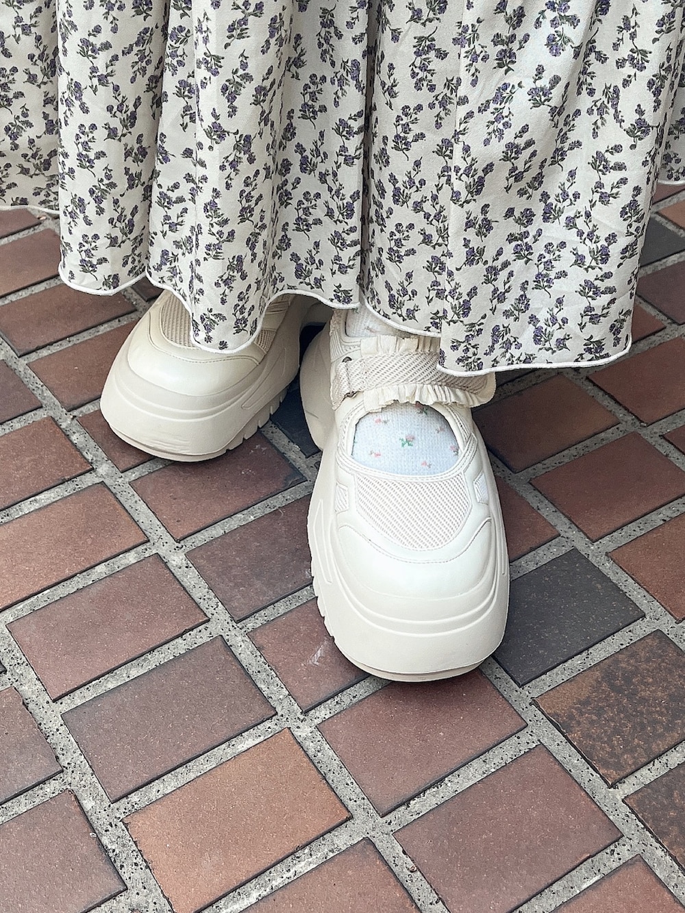 ブルー系のチェスターコート、グリーン系のスカート、ホワイト系のスニーカーを着用したレディースの冬コーディネートの7枚目の写真