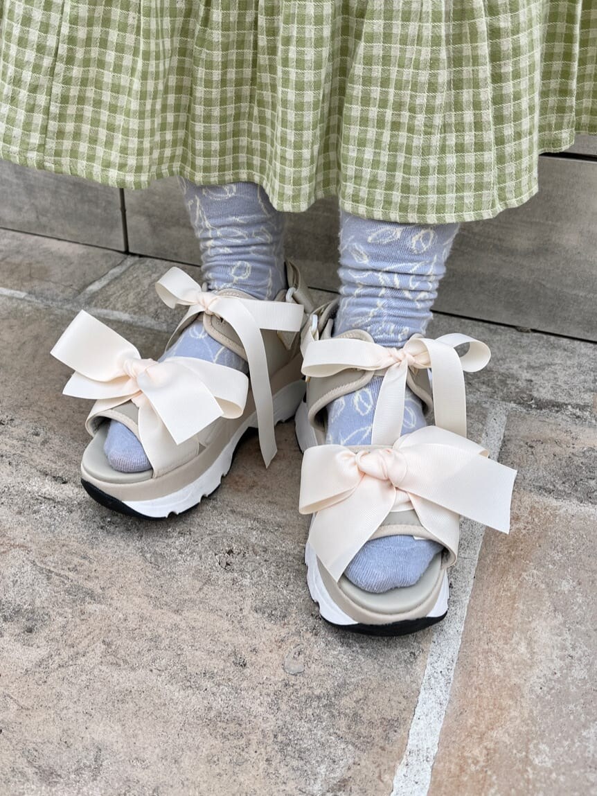 ホワイト系のチュニック、グリーン系のスカート、ホワイト系のサンダルを着用したレディースの春コーディネートの4枚目の写真