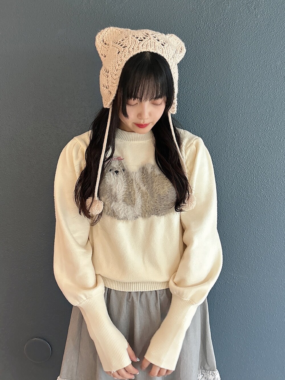 ホワイト系のニット/セーター、グレー系のスカート、ホワイト系のスニーカーを着用したレディースの秋コーディネートの7枚目の写真
