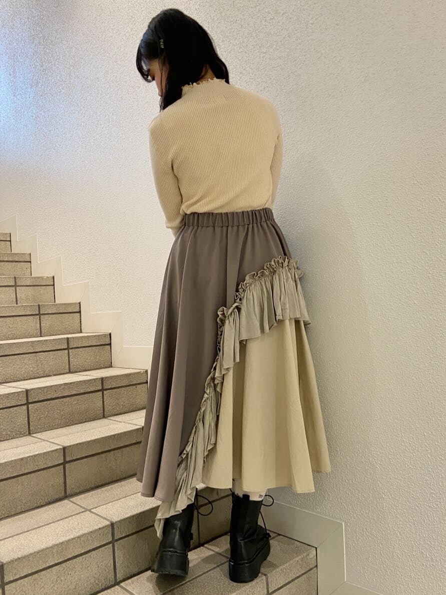 ブラック系のハンドバッグ、ブラック系のブーツ、ベージュ系のスカートを着用したレディースの冬コーディネートの7枚目の写真