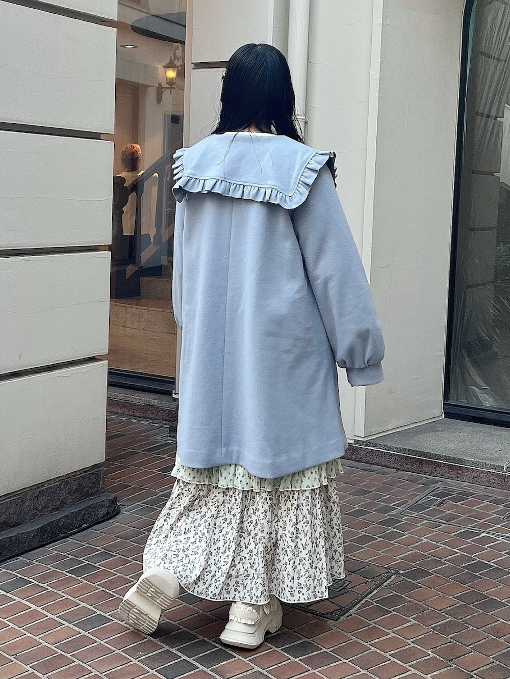 ブルー系のチェスターコート、グリーン系のスカート、ホワイト系のスニーカーを着用したレディースの冬コーディネートの3枚目の写真