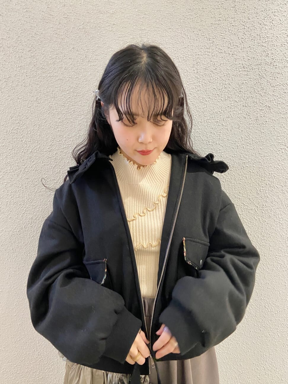 ブラック系のハンドバッグ、ブラック系のブーツ、ベージュ系のスカートを着用したレディースの冬コーディネートの4枚目の写真