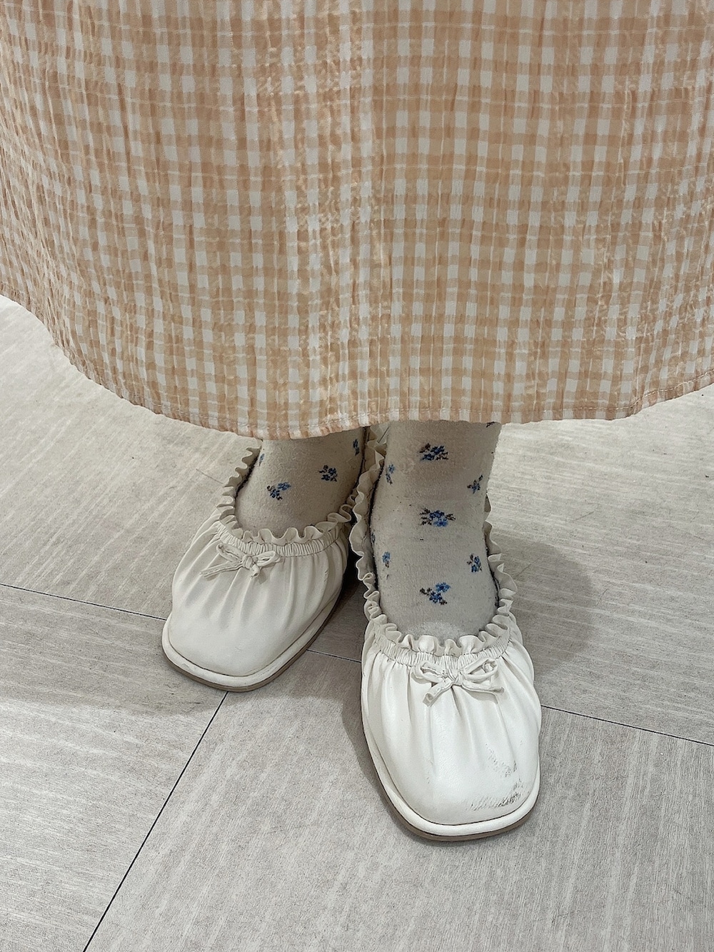 オレンジ系のワンピース、ホワイト系のトレンチコート、ホワイト系のパンプスを着用したレディースの春コーディネートの9枚目の写真