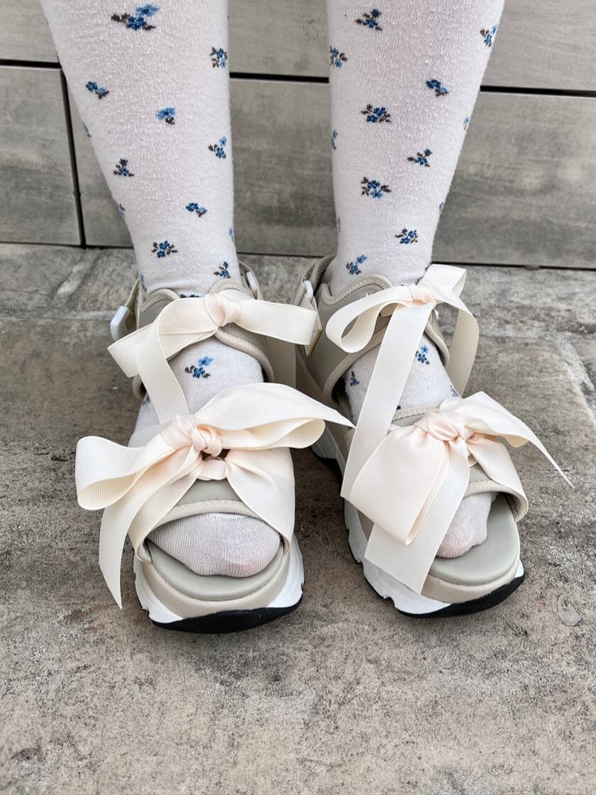 ブルー系のハンドバッグ、ホワイト系のサンダル、ブルー系のワンピースを着用したレディースの夏コーディネートの6枚目の写真