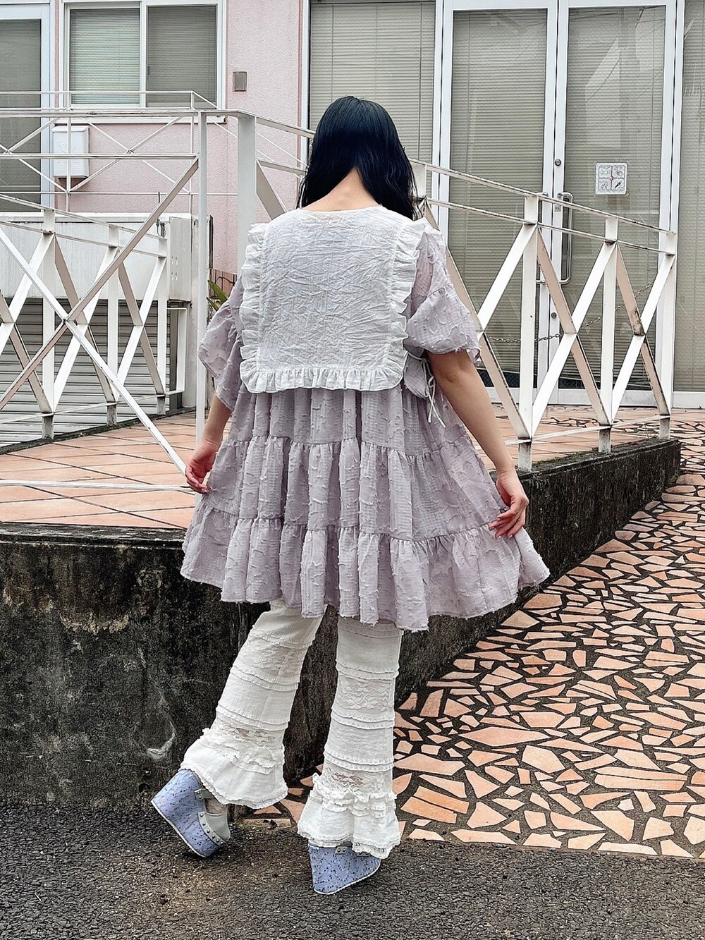 パープル系のワンピース、ホワイト系のスラックス、ブルー系のサンダルを着用したレディースの春コーディネートの3枚目の写真