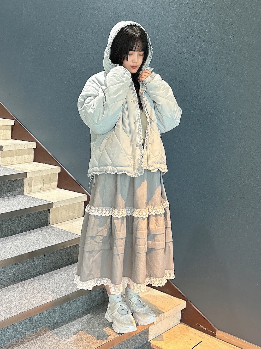 ブルー系のダウンジャケット/コート、ホワイト系のニット/セーター、グレー系のスカートを着用したレディースの秋コーディネートの5枚目の写真