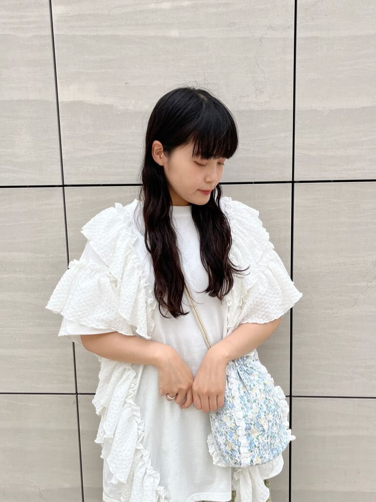 ホワイト系のチュニック、グリーン系のスカート、ホワイト系のサンダルを着用したレディースの春コーディネートの2枚目の写真