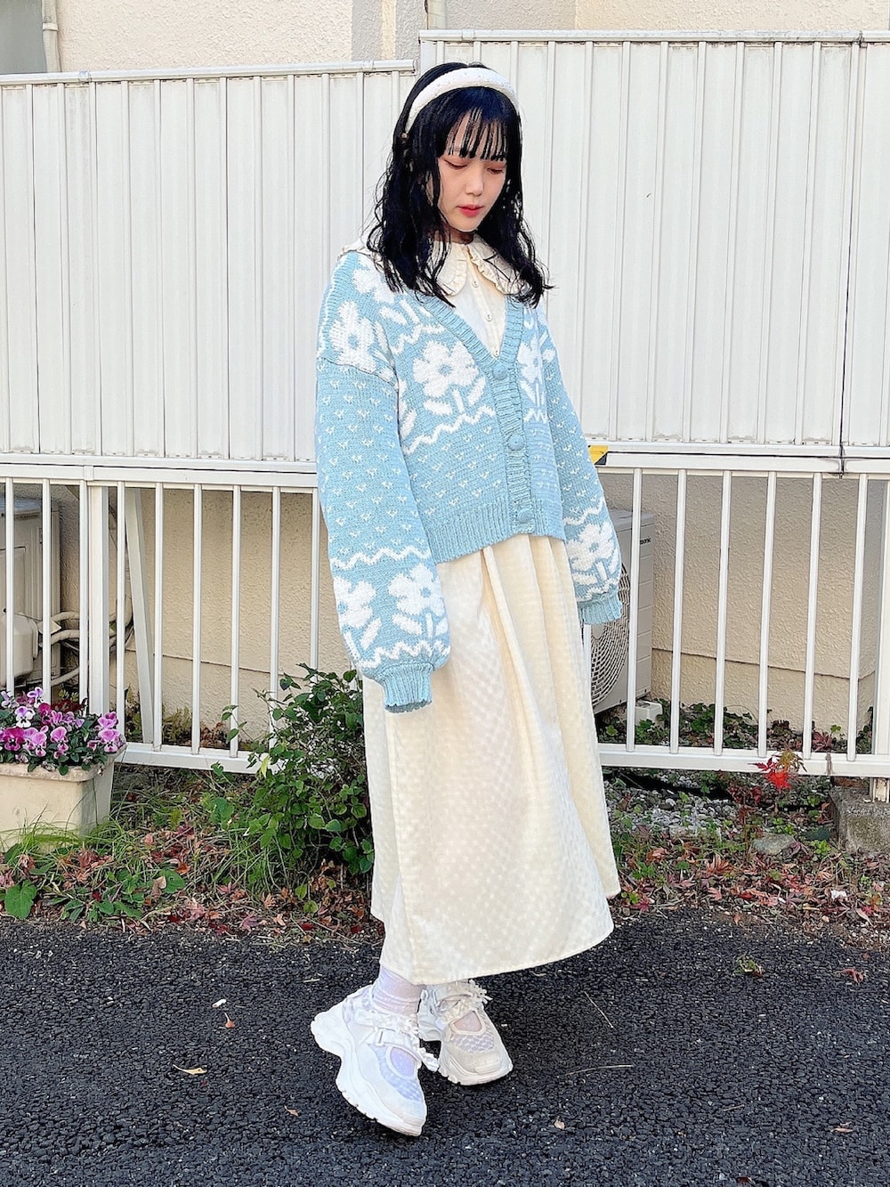 イエロー系のワンピース、ブルー系のカーディガン/ボレロ、ホワイト系のスニーカーを着用したレディースの冬コーディネートの2枚目の写真